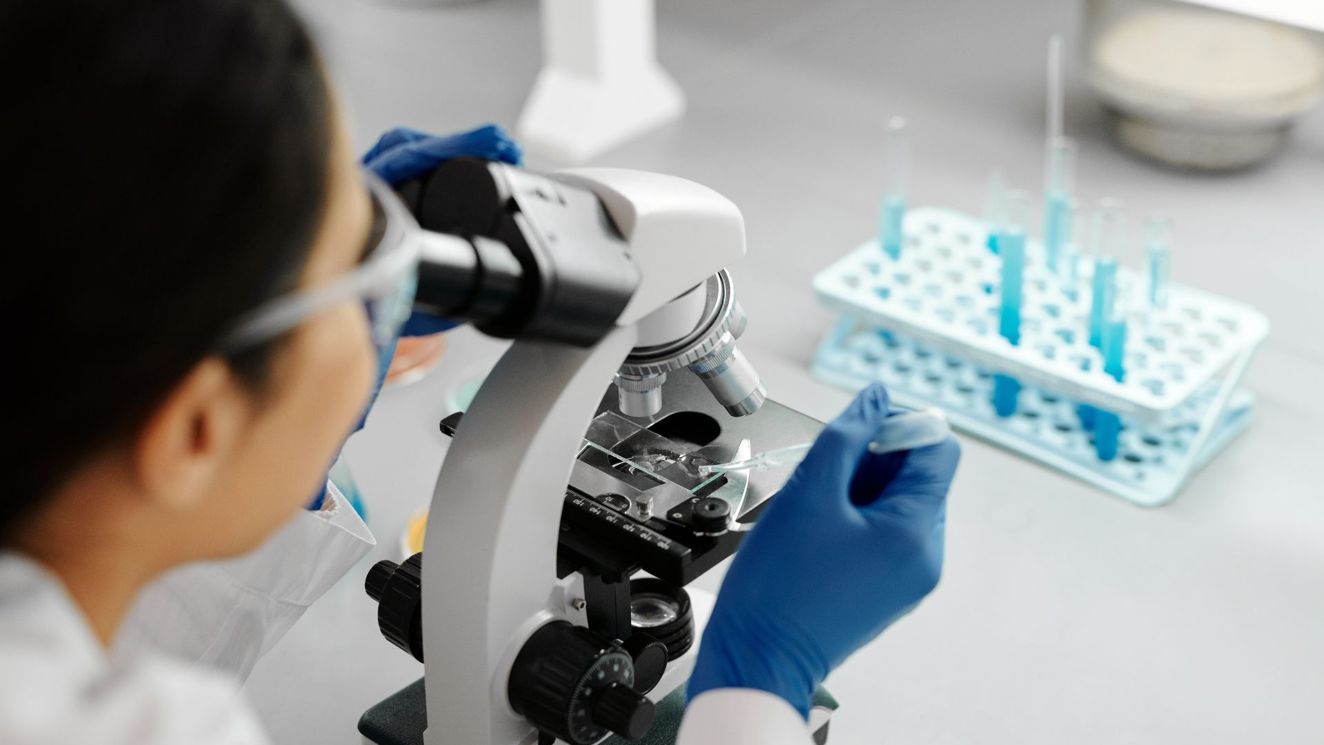 a woman with microscope doing some forensic test for drugs