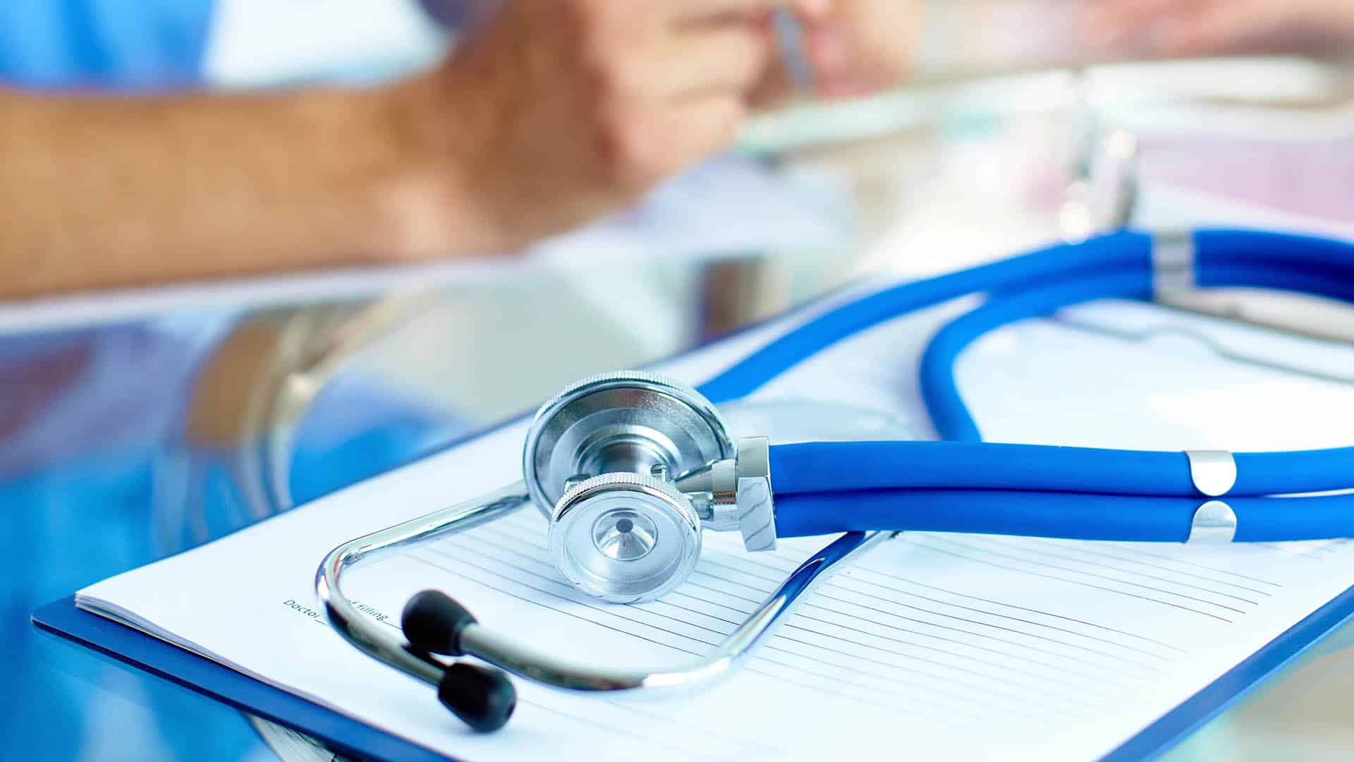 stethoscope and paper with doctor and patient in the background