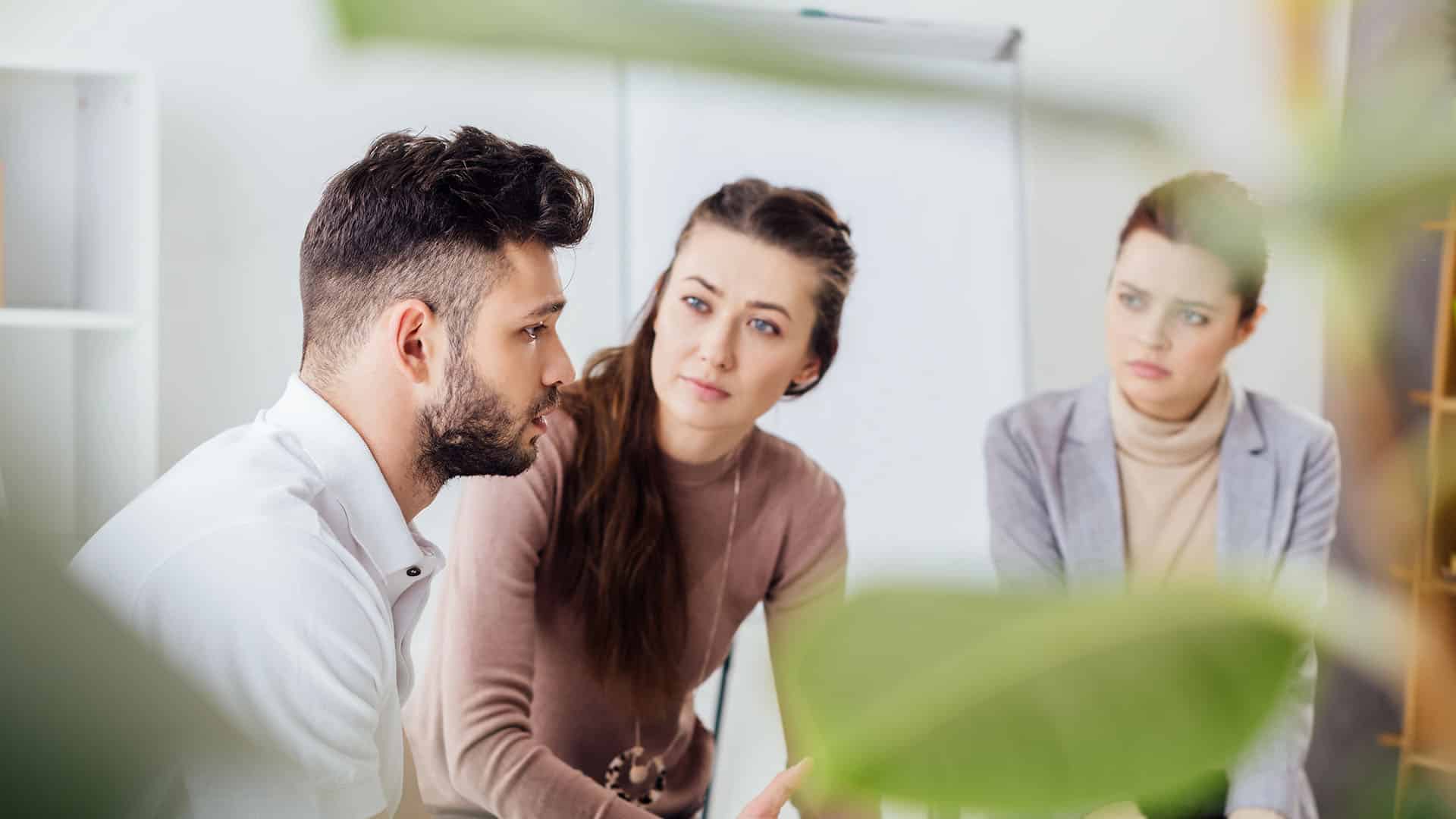 women and man sitting group therapy session
