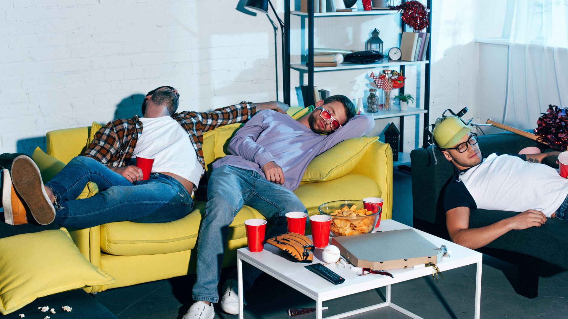Drunk young male friends sleeping on couches after home party