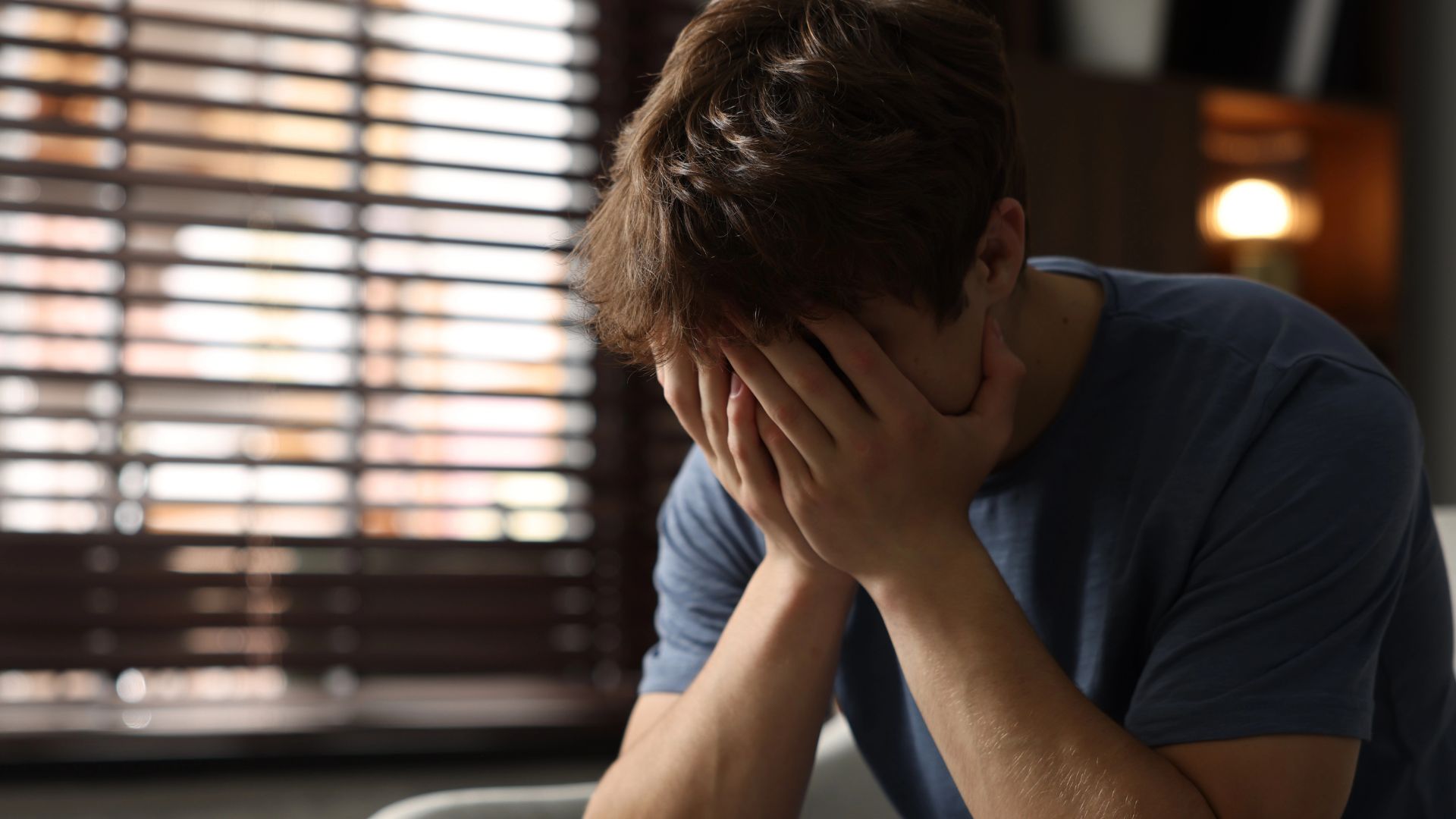 Depressed teenage boy on sofa at home