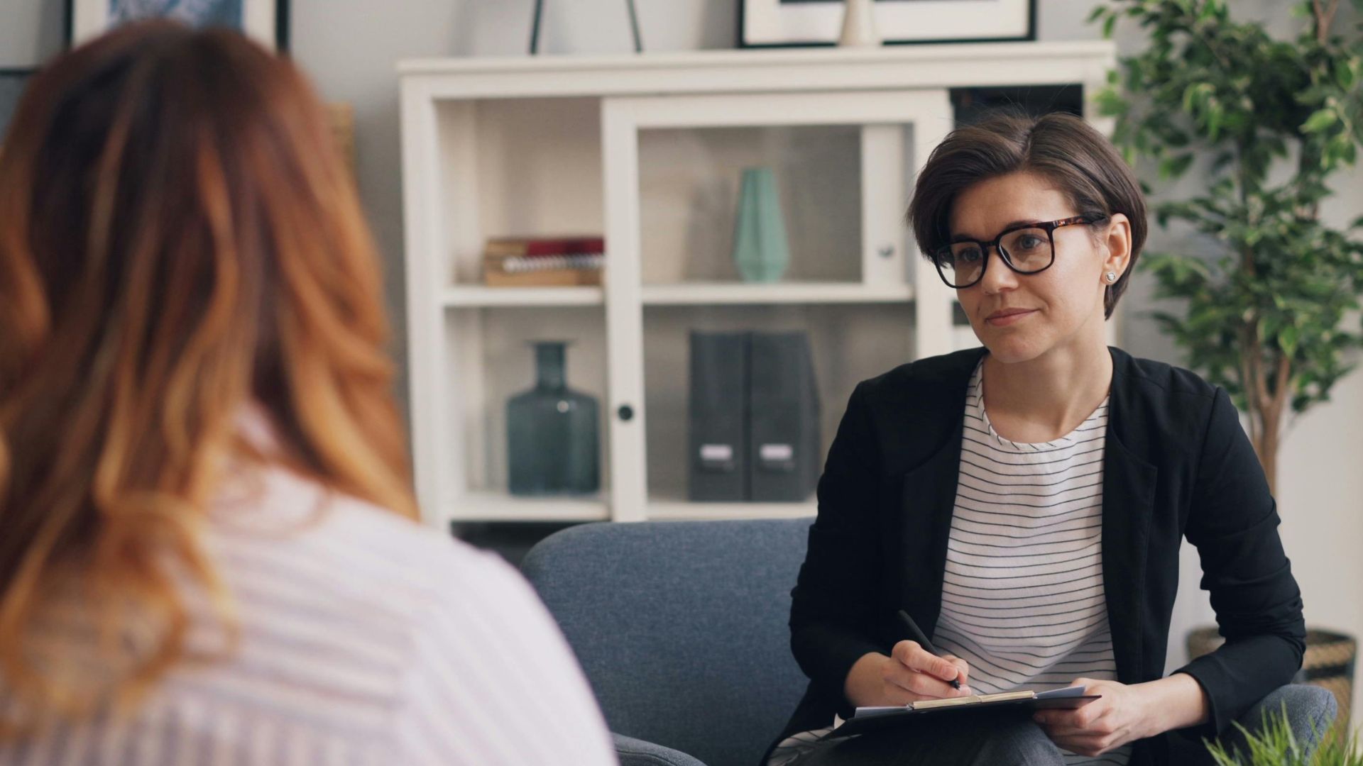 A woman sitting in a chair talking to another woman