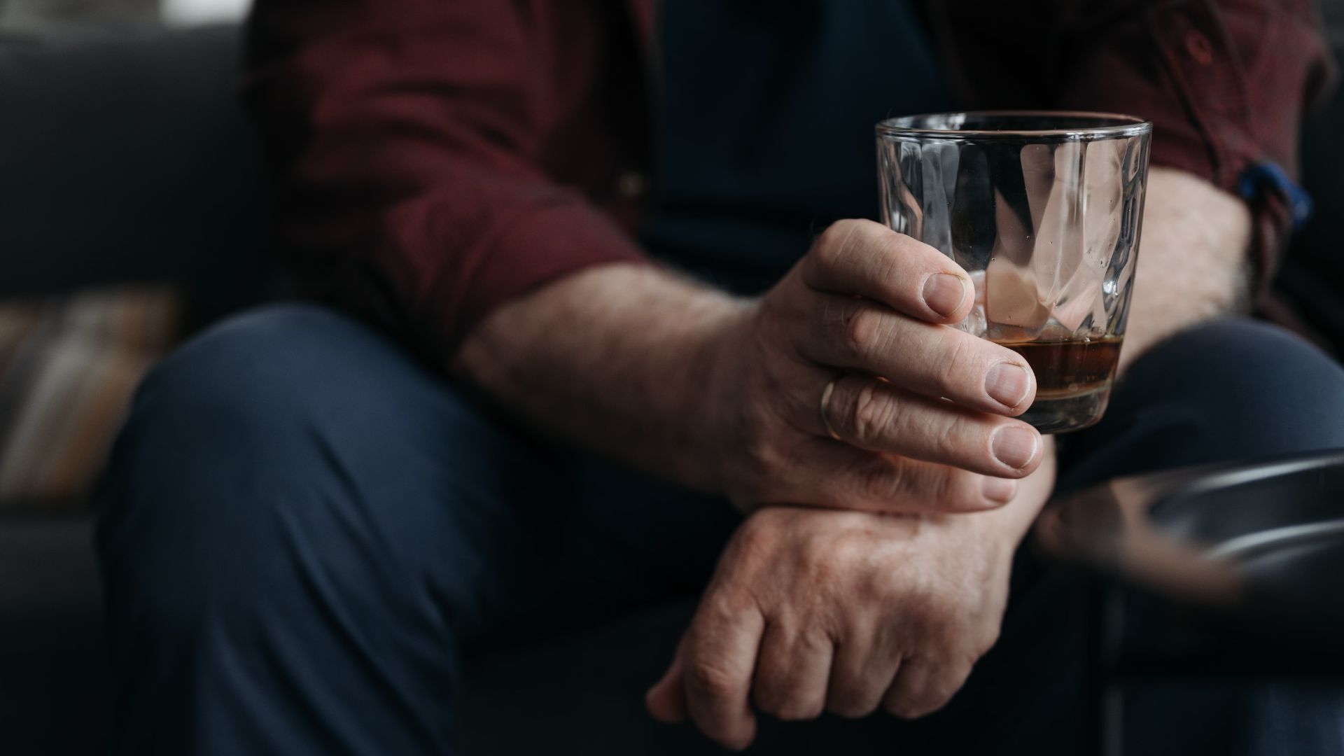 adult hand holding a whiskey glass indoors