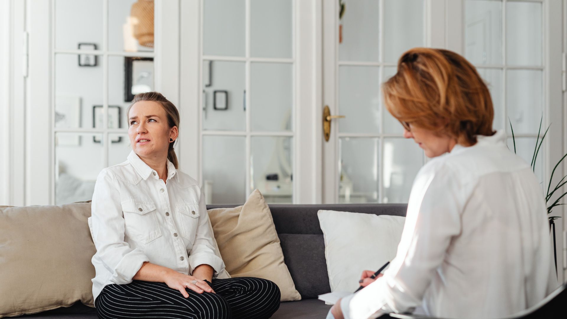 women sitting on sofa while having conversation