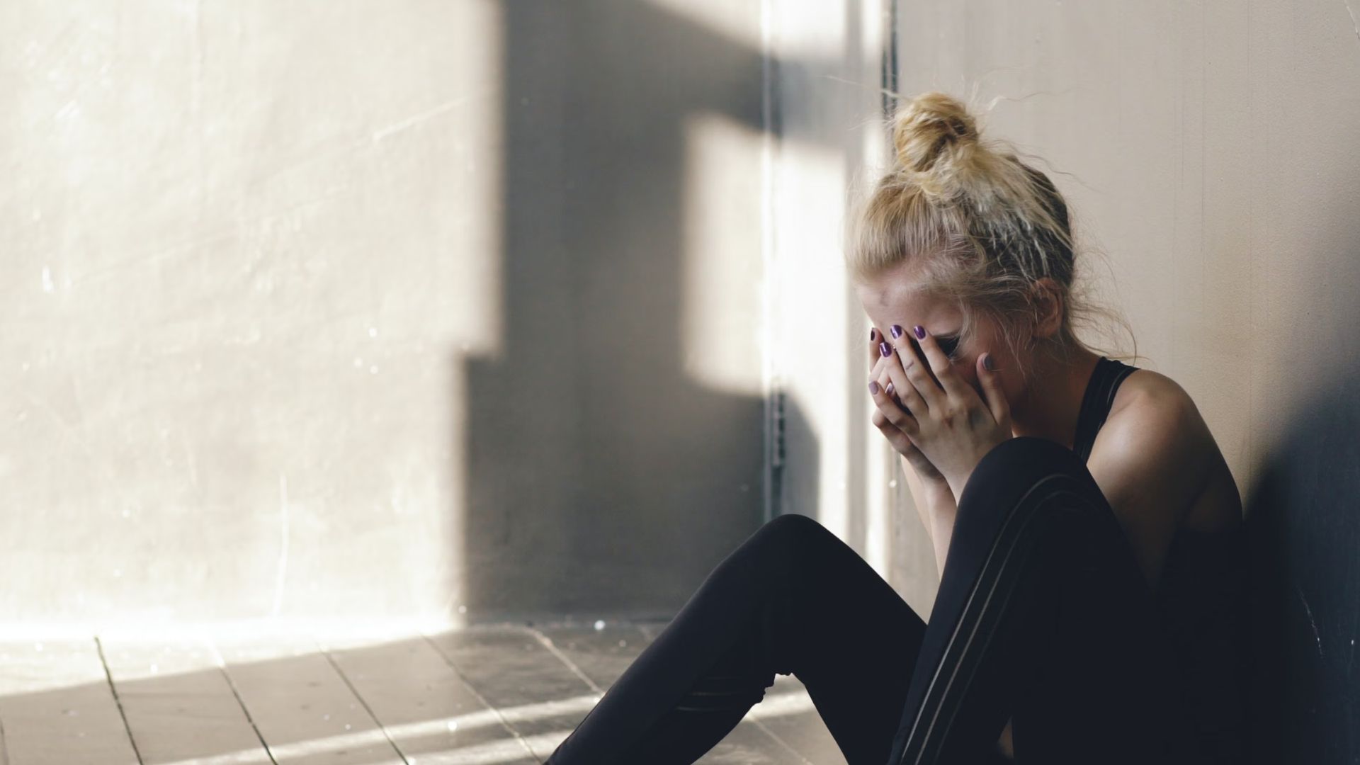 A woman sits barefoot on the floor