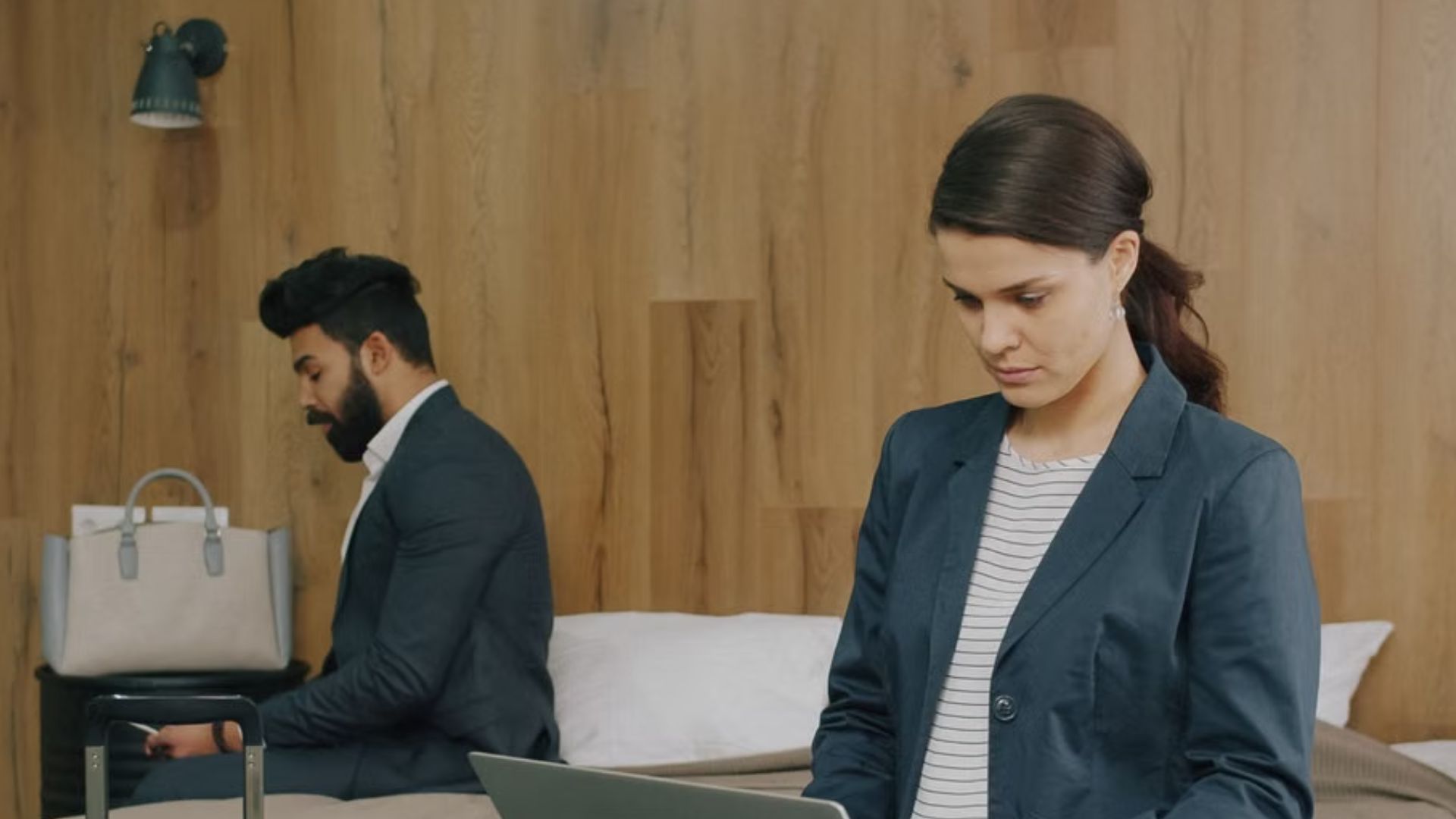A man and woman in business attire working on laptops