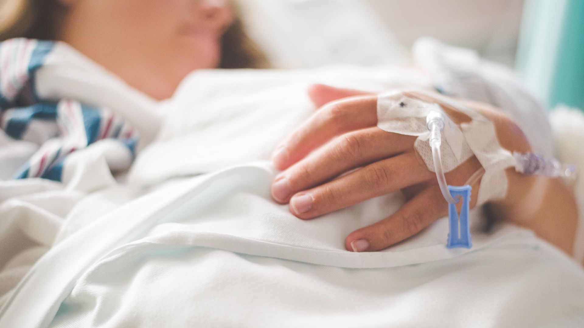 patient's hand with IV in a hospital setting